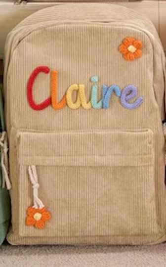 Close-up of a real khaki backpack with Claire in multi-colour yarn letters